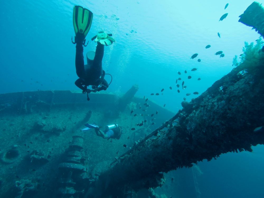 scuba divers exploring shipwrecks under the ocean