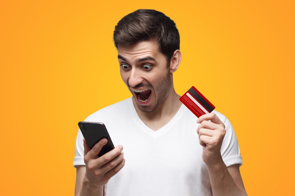 angry man holding credit card and phone shouting