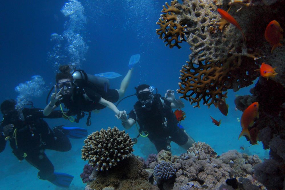 three scuba divers posing for photo under water