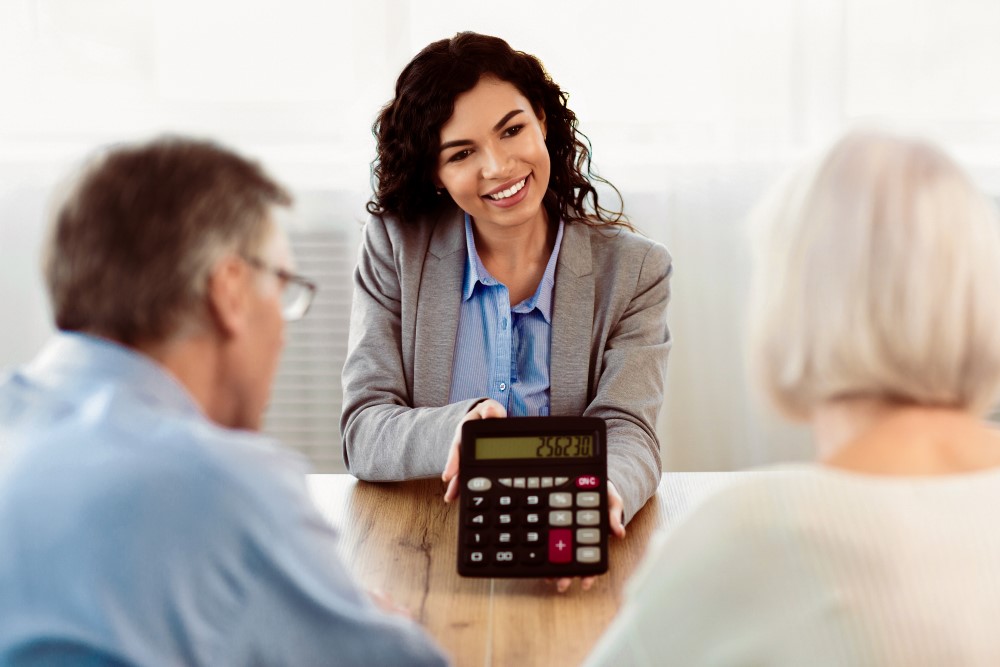 a women broker explaining the brokerage charges using broker calculator to a married couple