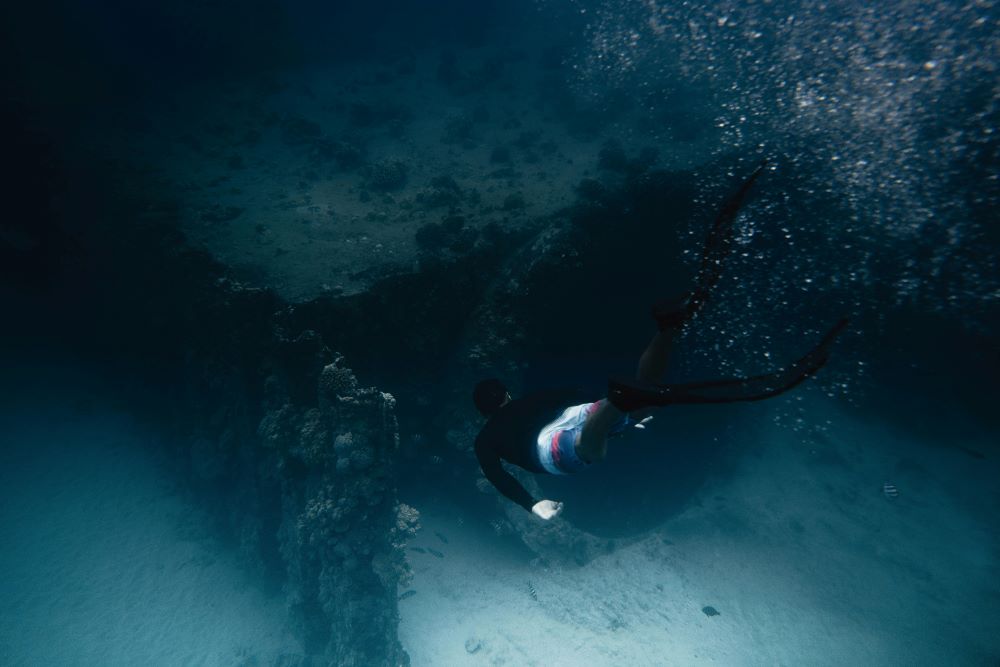 scuba diver near to a cave at underwater