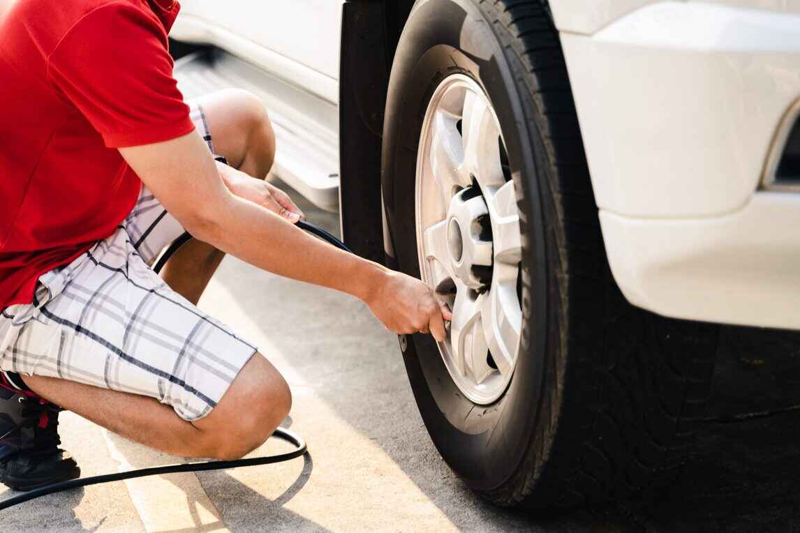 close up asian man inflating tire gas station