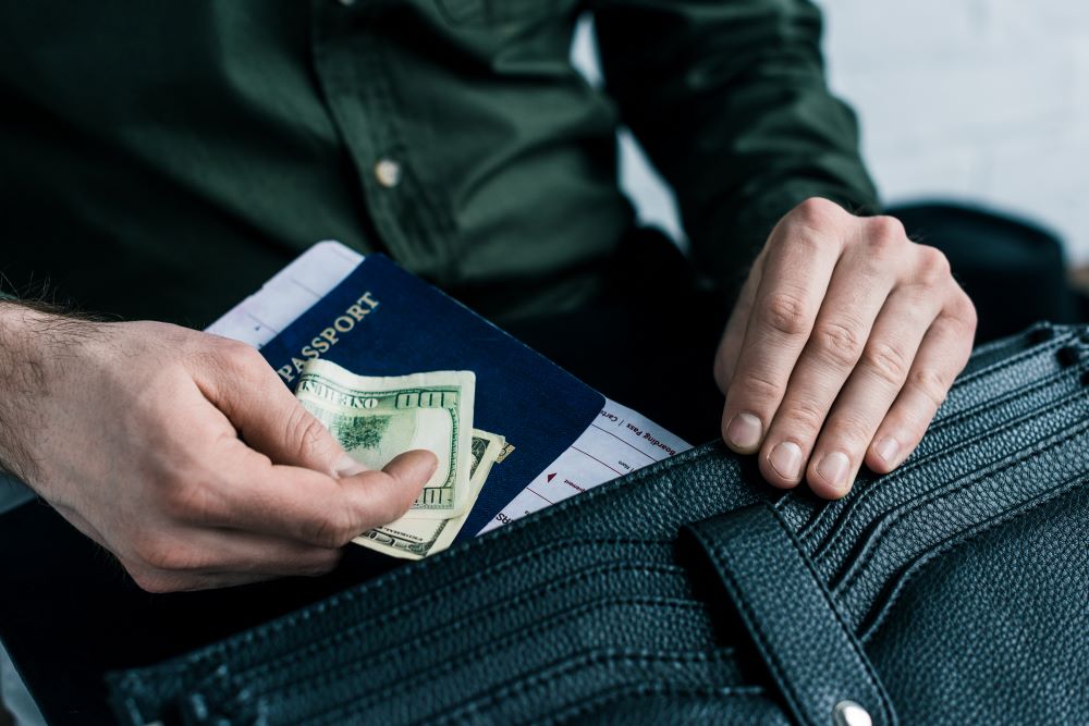 man putting passport and money to bag