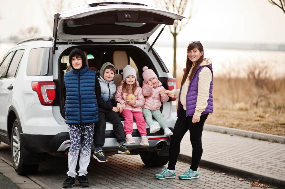 group of people standing by a family suv car