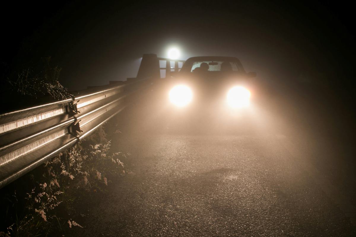 a person driving a car using fog lights while driving