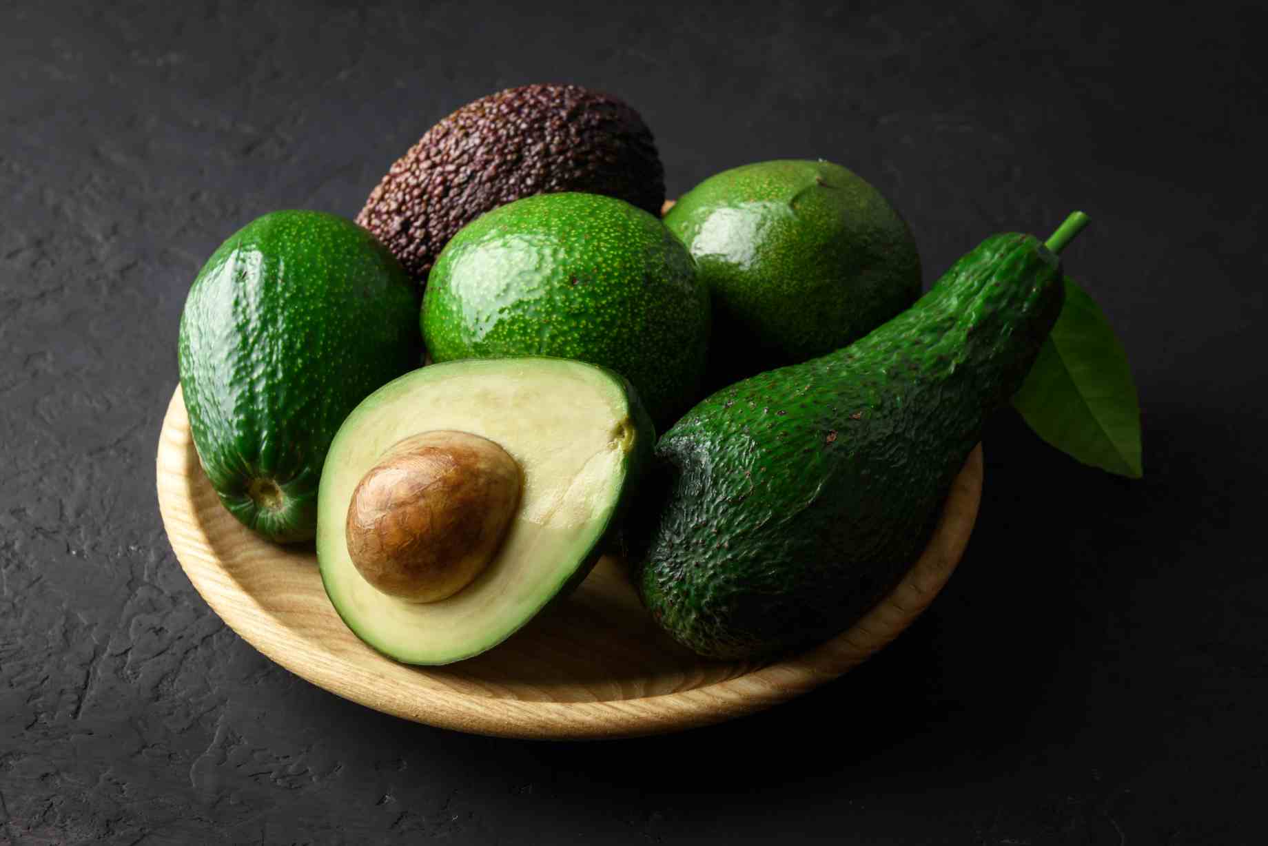 fresh avocado fruit on a wooden plate