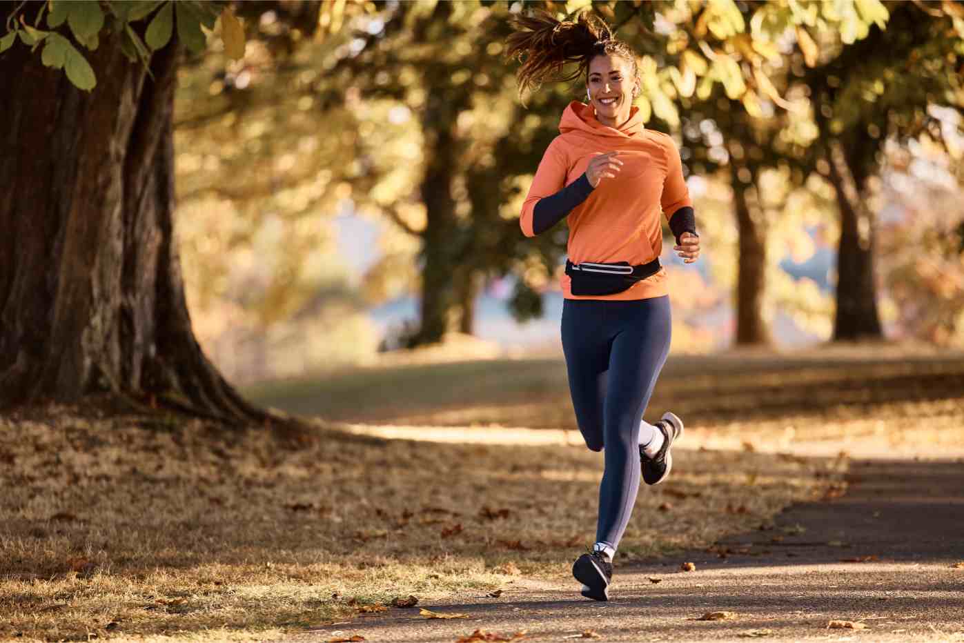 happy female athlete jogging on autumn day