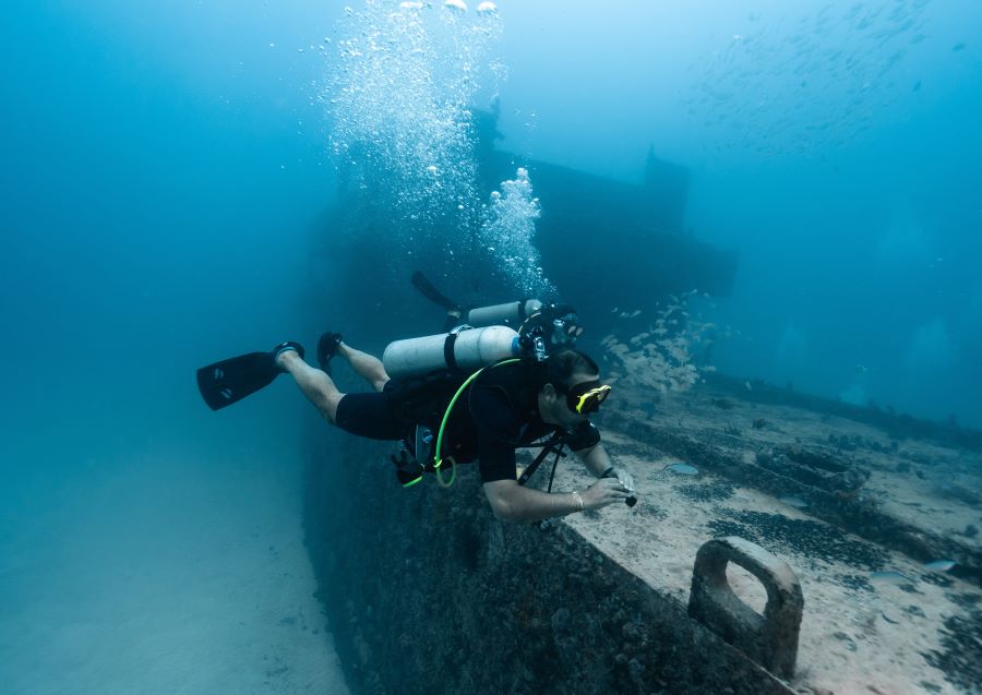 scuba diver exploring old wrecked ship