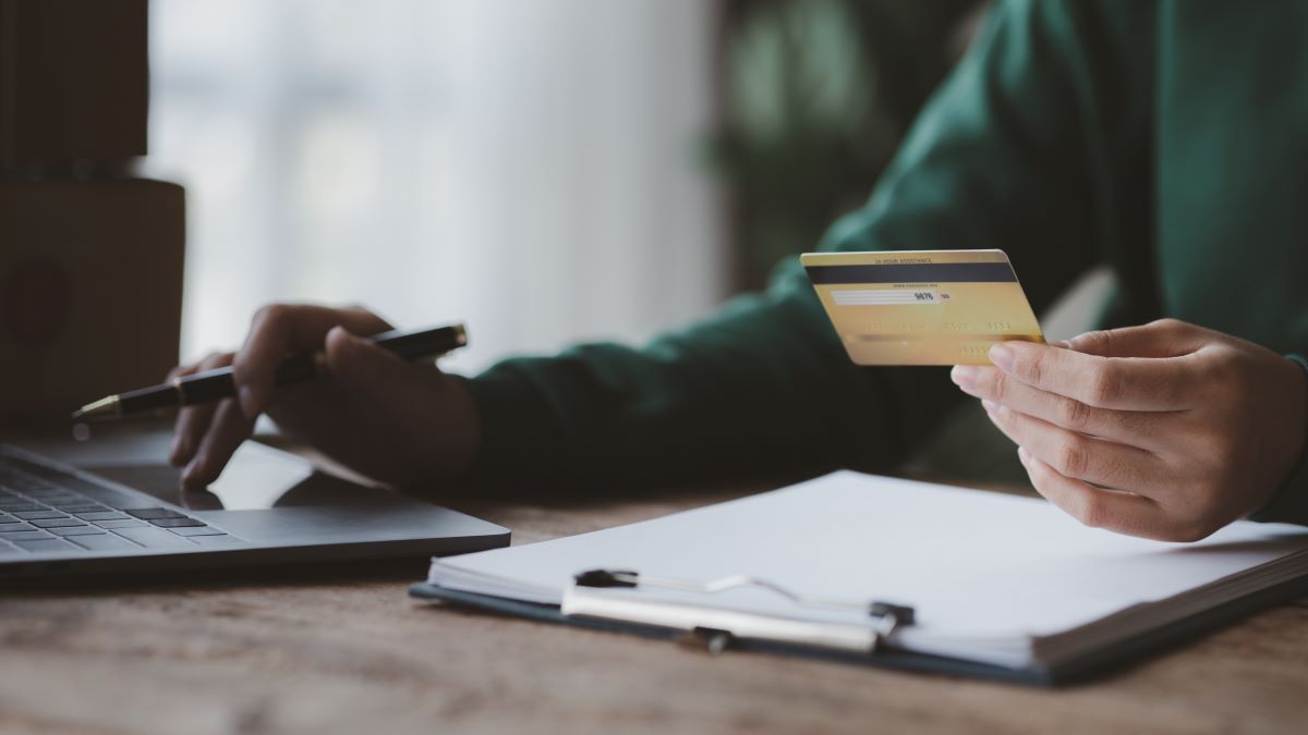 an individual sitting infront of laptop holding a credit card