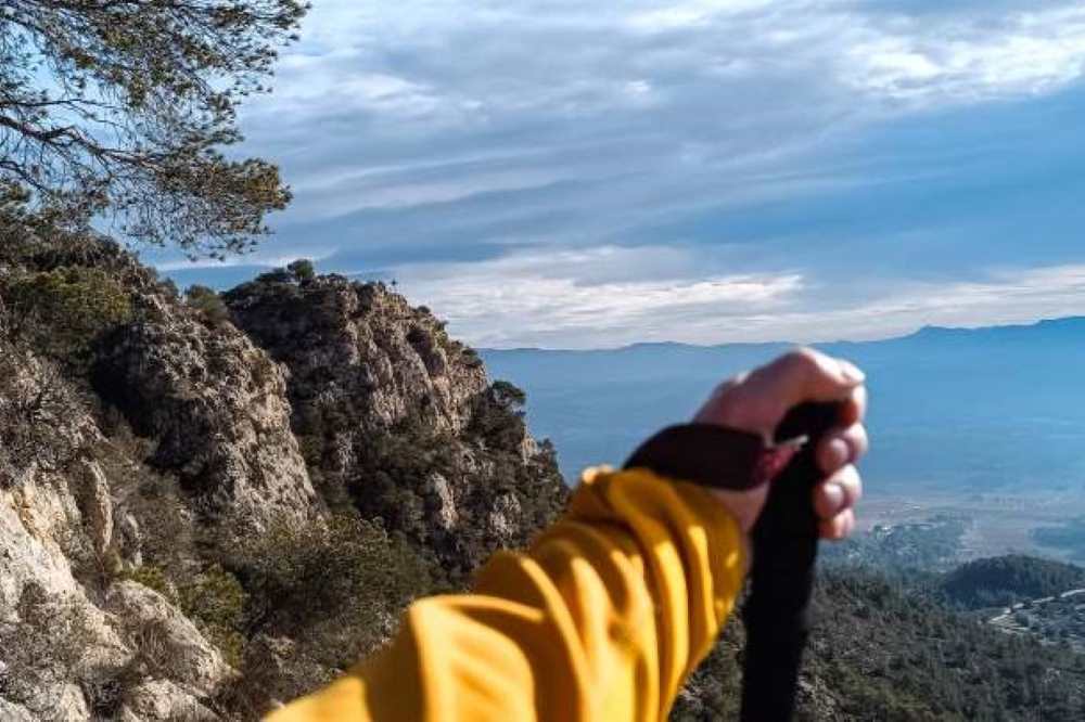 anonymous male trekking with a pole in the hill top