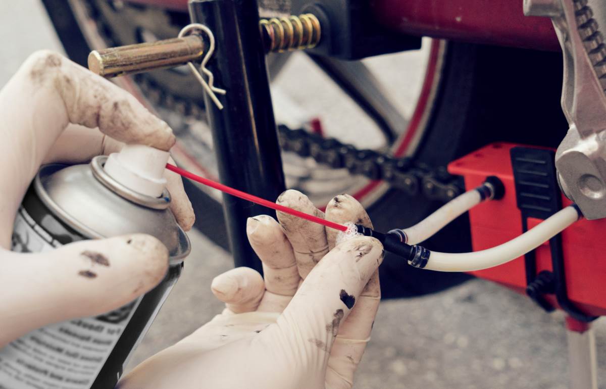 man cleaning motorcycle chain with a device