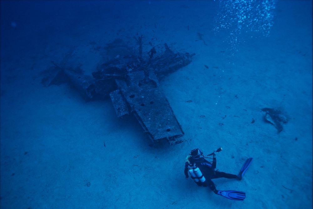 scuba diver near shrinken plane underwater