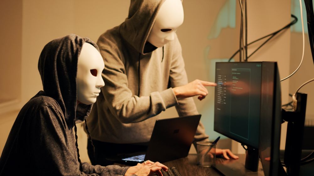 two hackers with mask stealing information 