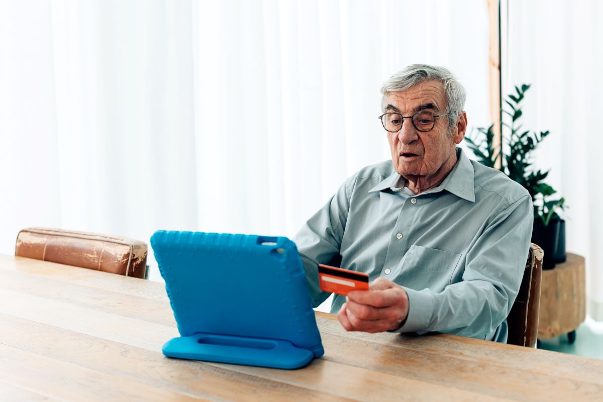 old man using wireless technology for opening a senior citizen savings scheme account in home