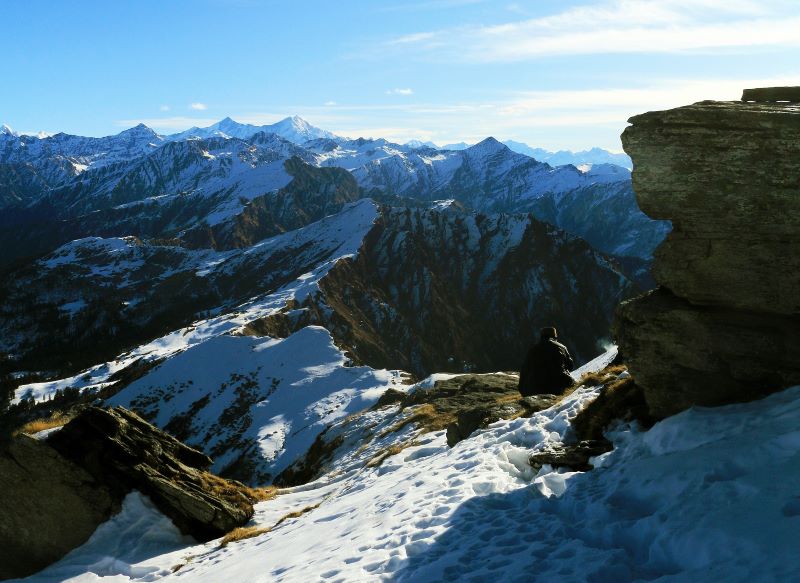 view of mountains and a guy sitting in snow