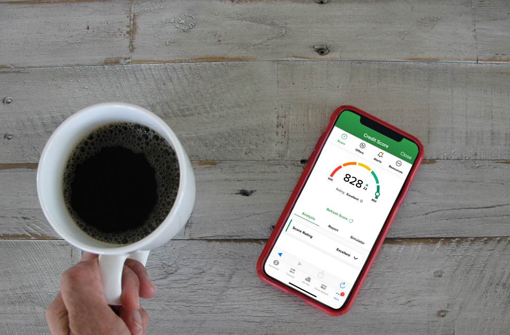 A person checking credit score on bank app in mobile while drinking coffee in the morning