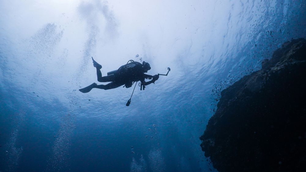 scuba diver swimming by holding camera