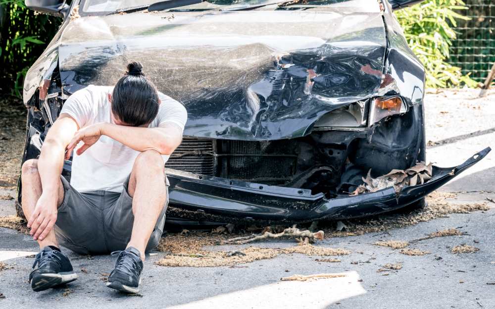 man crying infront of damaged car