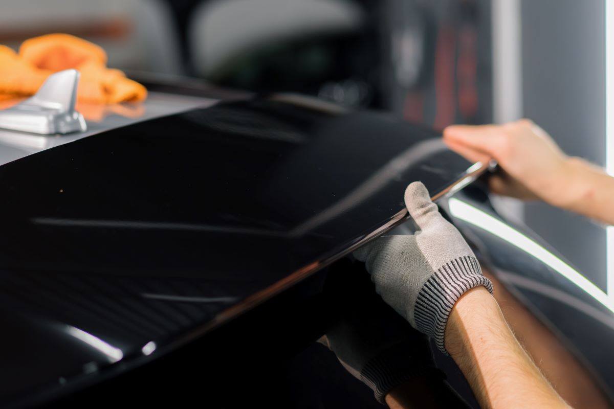 a car mechanic installing the car spoiler in a modern luxury car