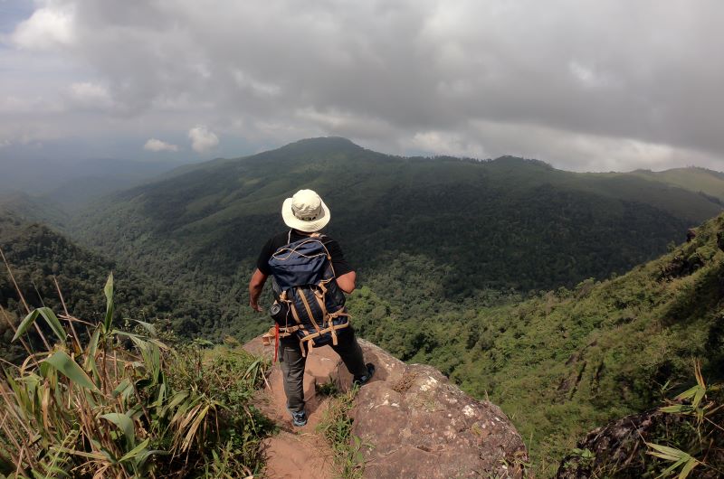 a trekking guy with hat on top of hill