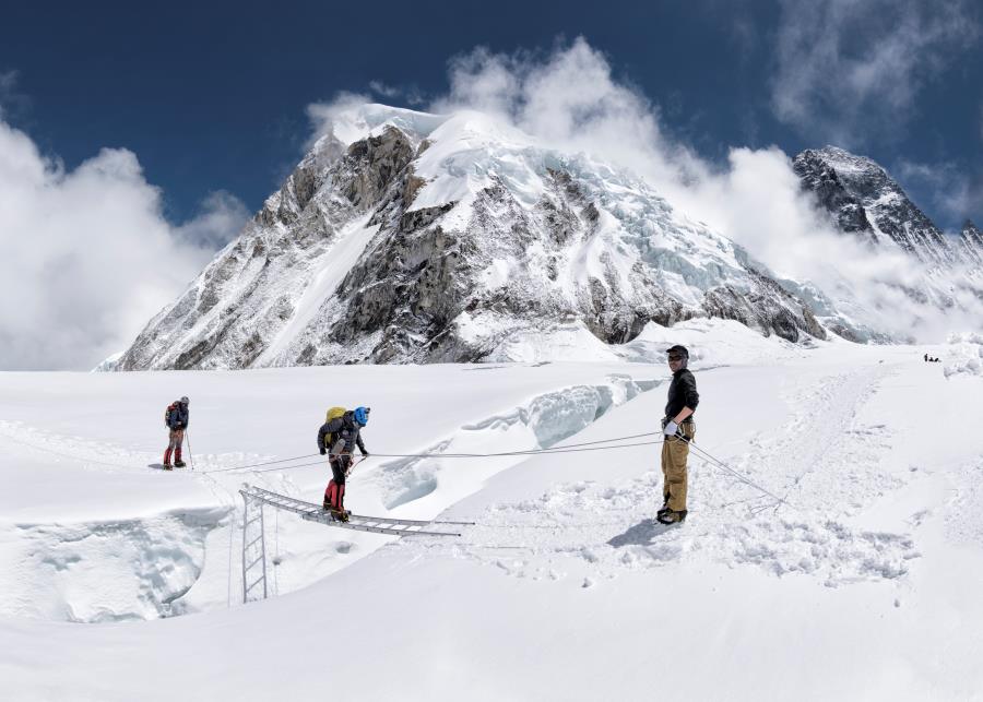 three mountaineers passing crevasse