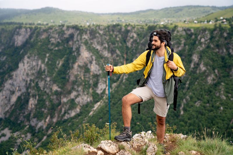 man with yellow jacket at the top of hill