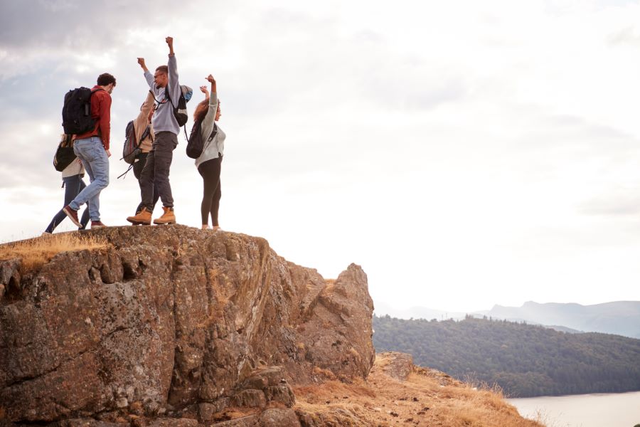 five hikers enjoying time after reaching at top of the hill