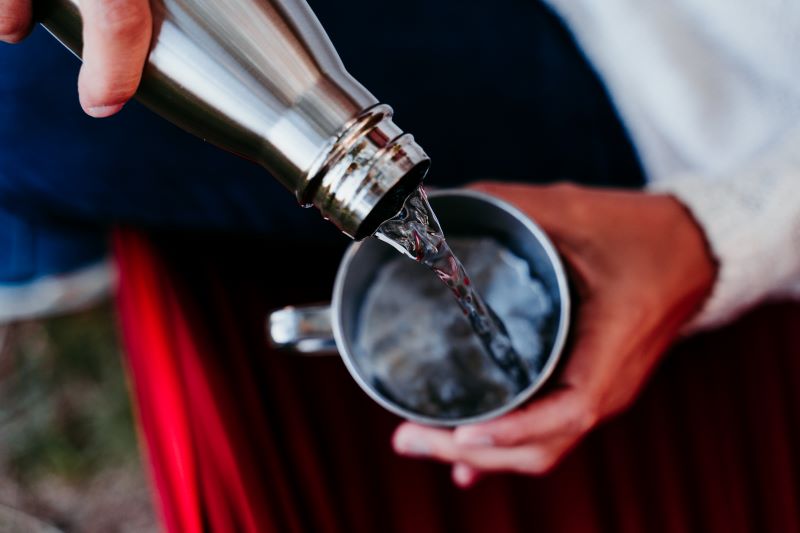 woman holding thermos pouring hot water