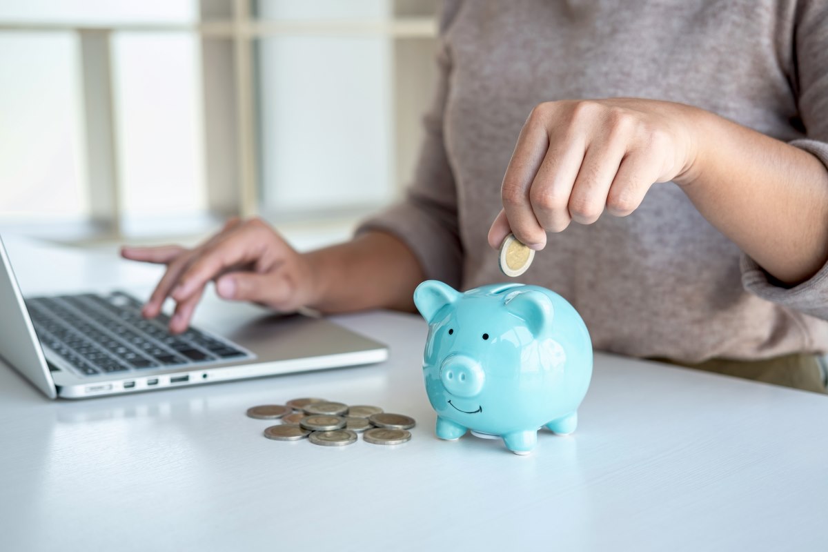 woman putting coins into piggy bank