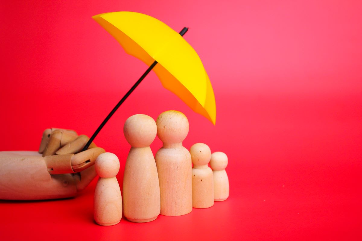 a family of wooden figures protected by an umbrella