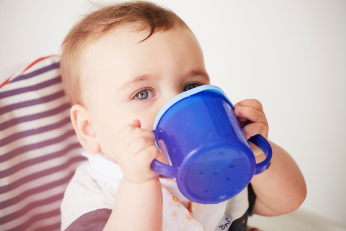 baby holding a cup and drinking