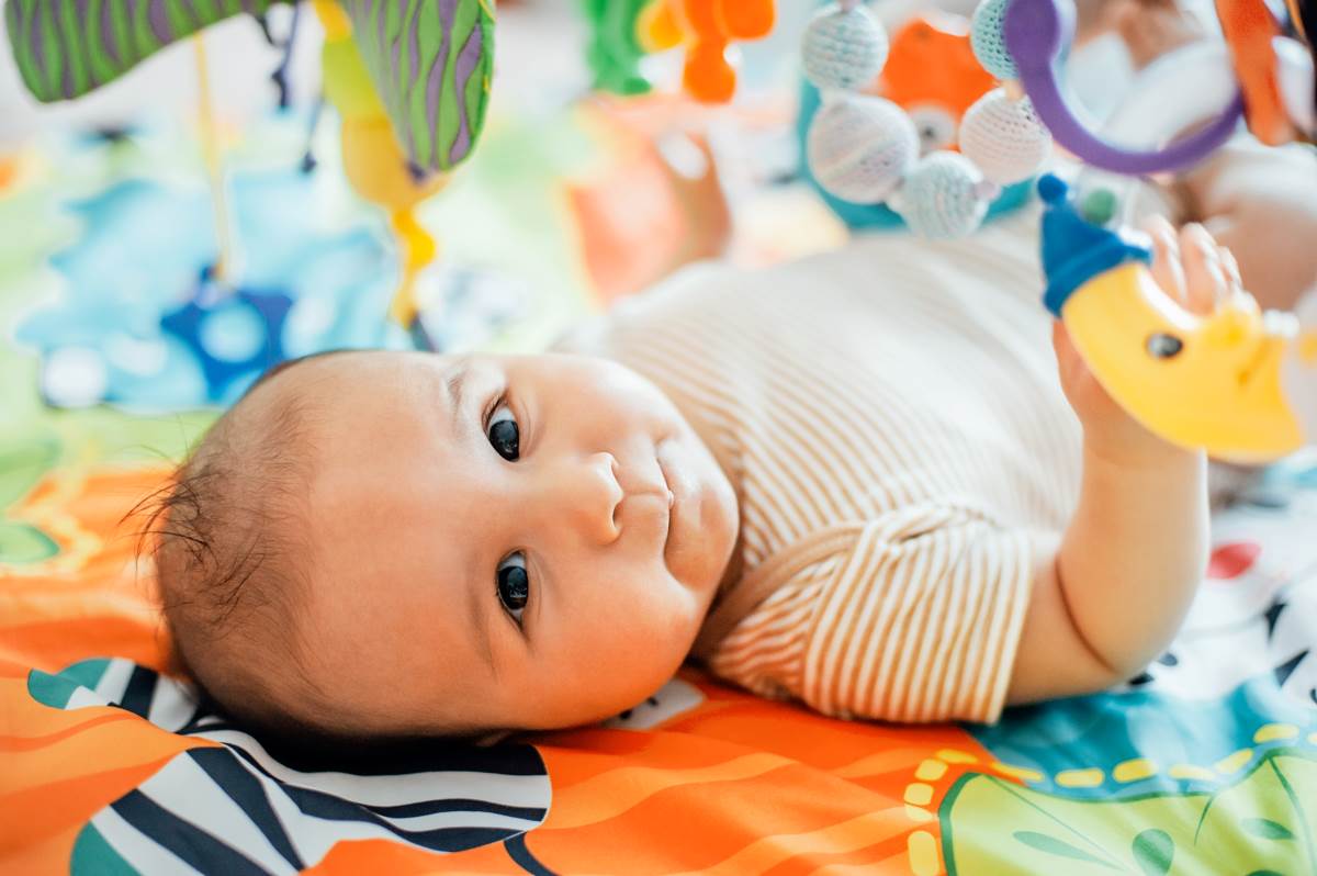 baby lying on a bed playing