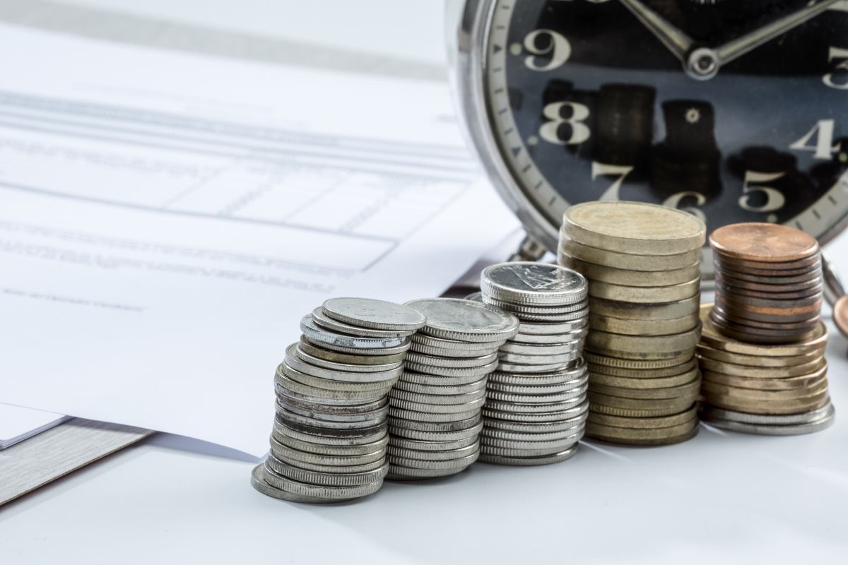 closeup shots of stacks of coins near a clock