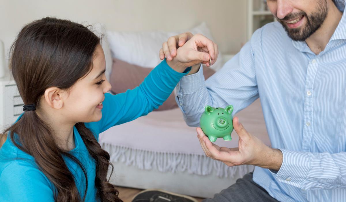 father and daughter putting money in piggy bank