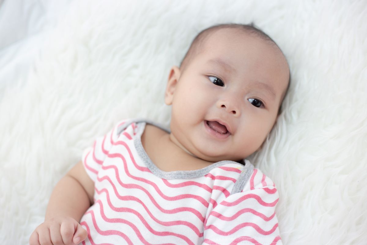 happy baby lying on bed