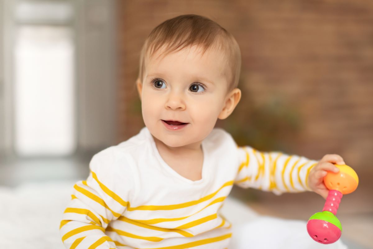 infant girl playing with rattle toy