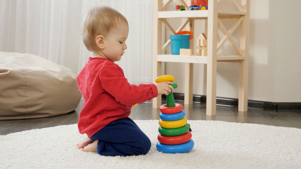 little boy playing with colourful toy pyramid