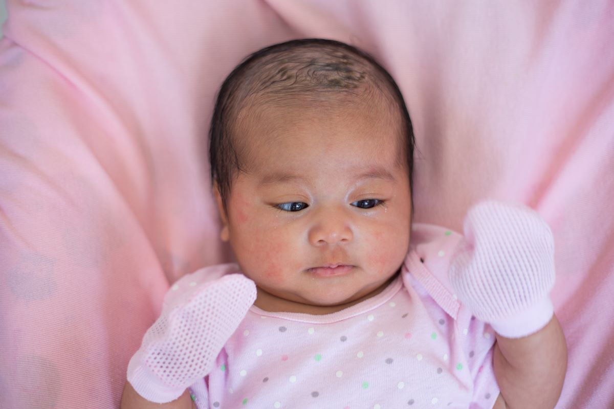 newborn girl lying on pink blanket