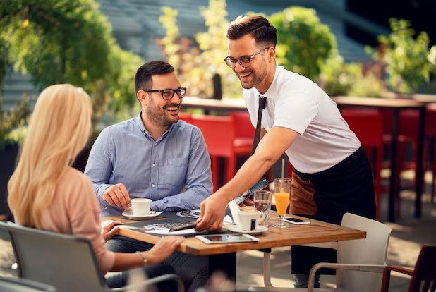 smiling waiter serving guests