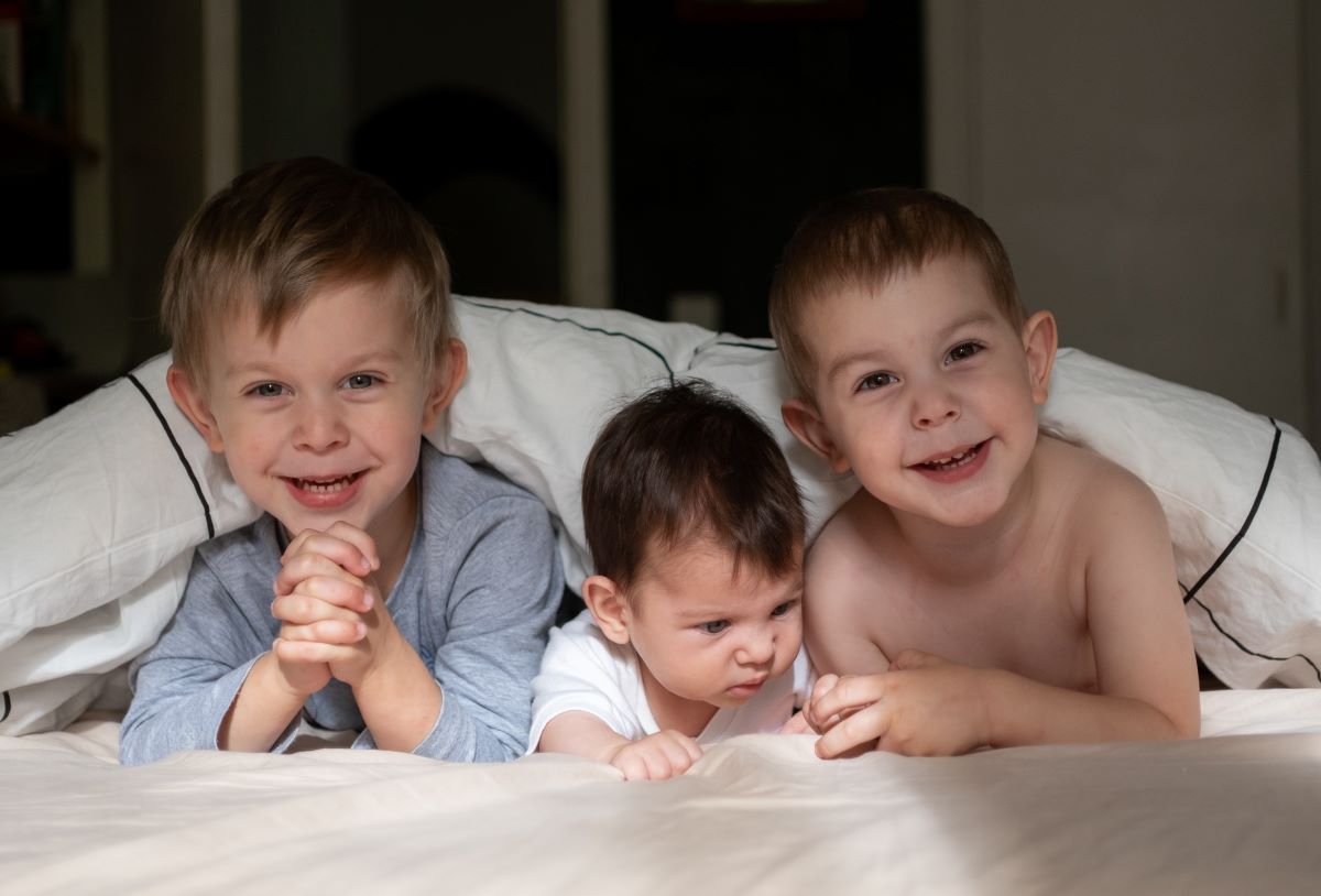 three little kids lying on bed